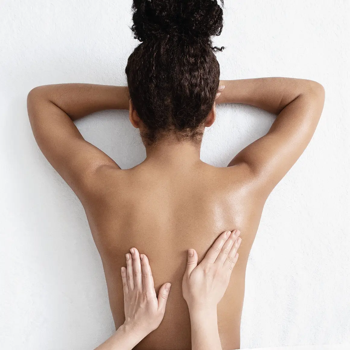 Vista trasera de mujer recibiendo un masaje terapéutico relajante en la espalda.